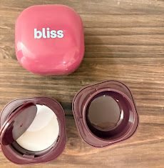 Bliss travel jars in pink and purple, one opened to show the leak proof seal.