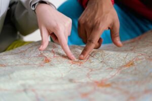 Close-up of diverse hands pointing at a paper map, symbolizing travel planning and navigation.