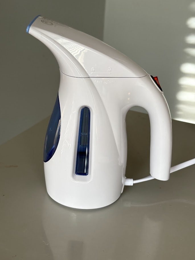 Side view of a blue and white HiLIFE portable handheld clothing steamer (a compact travel steamer) with its power switch clearly visible.