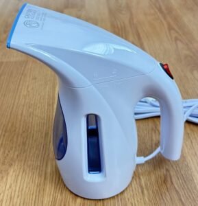 A blue and white HiLIFE portable handheld clothing steamer with a white power cord, sitting on a wooden floor.
