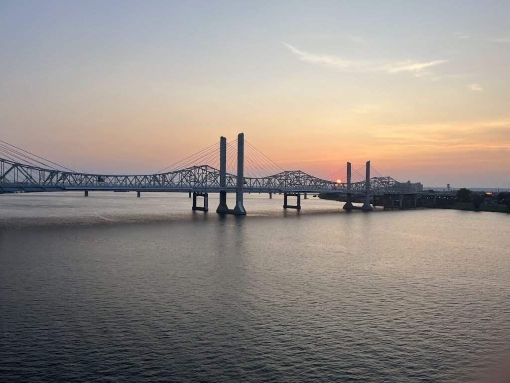 A wide-angle view of the Big Four Bridge, a historic steel truss pedestrian bridge crossing the Ohio River from Louisville, Kentucky, to Jeffersonville, Indiana. Louisville travel guide tips.