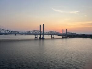 A wide-angle view of the Big Four Bridge, a historic steel truss pedestrian bridge crossing the Ohio River from Louisville, Kentucky, to Jeffersonville, Indiana. Louisville travel guide tips.