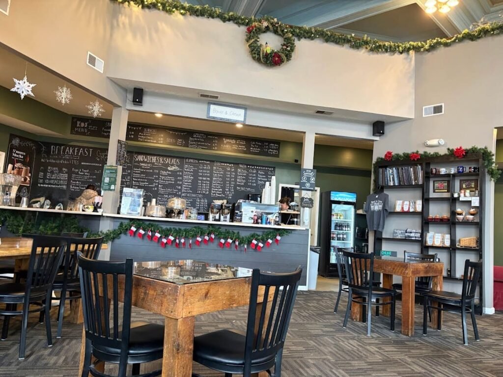 The cozy interior of Beans-n-Cream in Cedarville, Ohio, featuring a large chalkboard menu, festive holiday garlands with stockings, and rustic wooden tables.