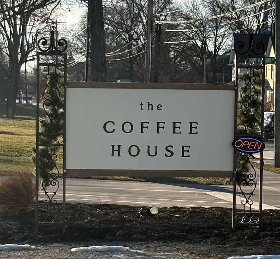 A large white outdoor sign for "the COFFEE HOUSE" in Plymouth, Ohio, held by black wrought iron posts with an "OPEN" sign. A Relaxing coffee shop.