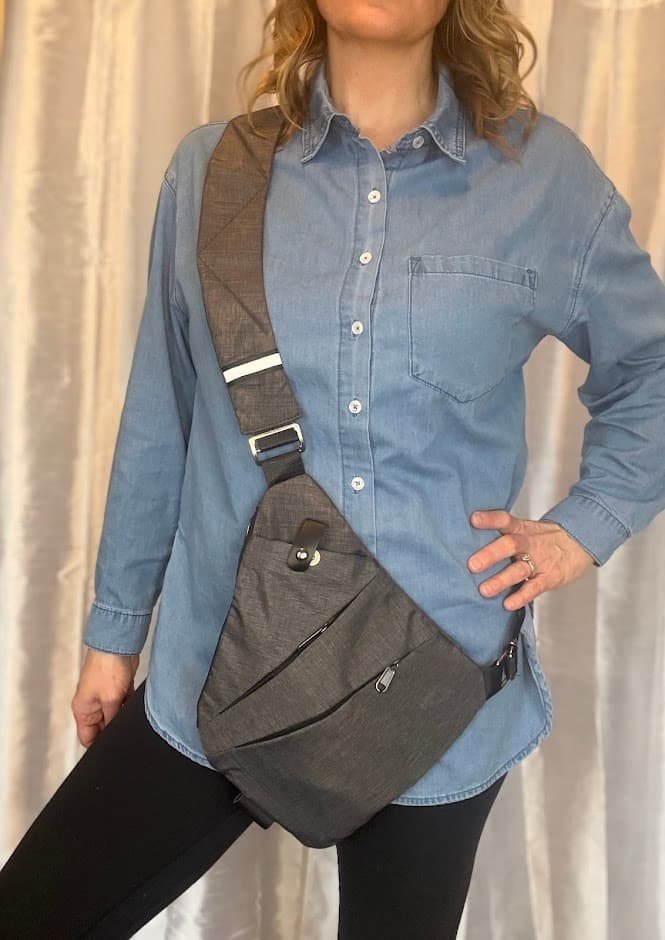 Best anti theft crossbody bag for travel in charcoal gray, worn over a blue denim shirt, highlighting its slim, secure, and ergonomic profile.