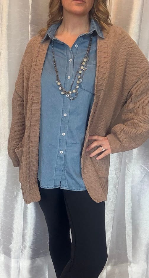 A woman modeling a lightweight denim shirt for women layered under a cozy tan cardigan, styled with a layered beaded necklace and black leggings.