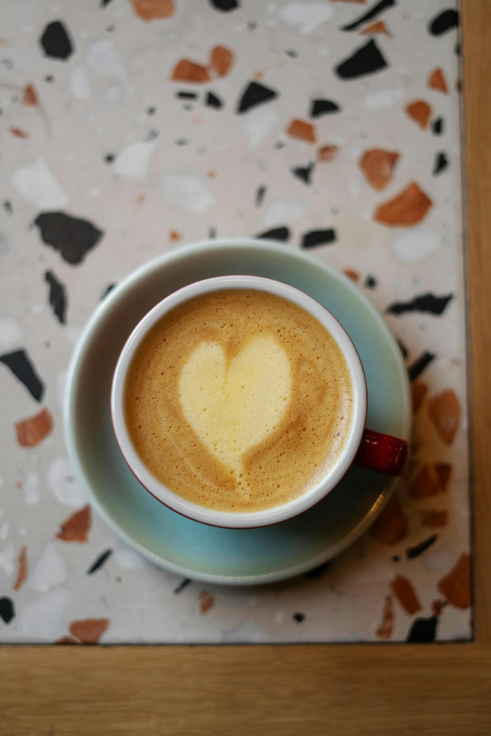 Top view of a cappuccino with heart-shaped foam in a blue cup, perfect for coffee lovers.