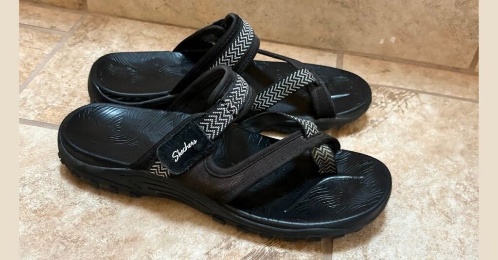 A pair of black Skechers Women's Reggae Trailway flip-flop sandals, shown to have a durable sole and comfortable straps, representing the best women travel sandals for walking.