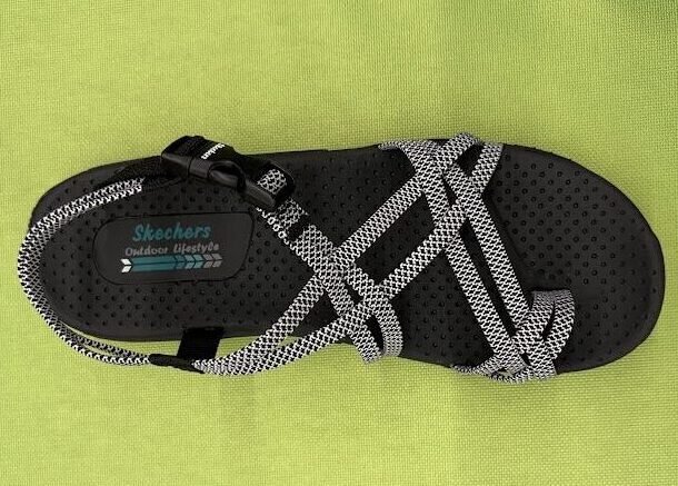 Close-up view of a black and white Skechers Women's Reggae Irie Mon sandal showcasing the shock-absorbing midsole, designed as a top option for best sandals for travel walking.