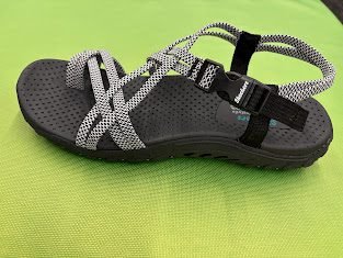 Close-up view of a black and white Skechers Women's Reggae Irie Mon sandal showcasing the shock-absorbing midsole, designed as a top option for best sandals for travel walking. Side View