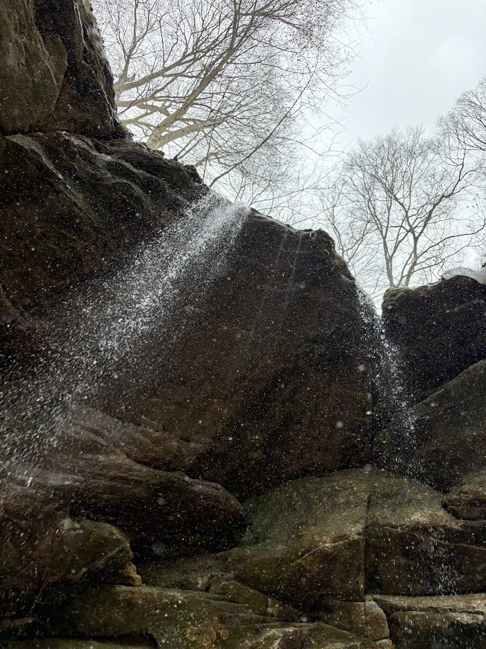 A close-up view of water cascading over the sandstone cliffs at Big Lyons Falls in Mohican State Park during a winter hike