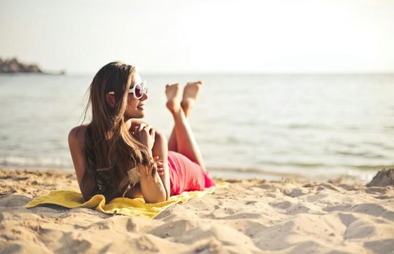 A woman in a pink swimsuit enjoys a sunny day relaxing on the beach.