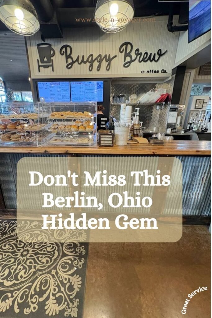 The wooden service counter at Buggy Brew Coffee Co. in Berlin, Ohio. It features a corrugated metal front, a glass display case filled with fresh pastries and cookies, and the "Buggy Brew" logo on a white shiplap wall.
