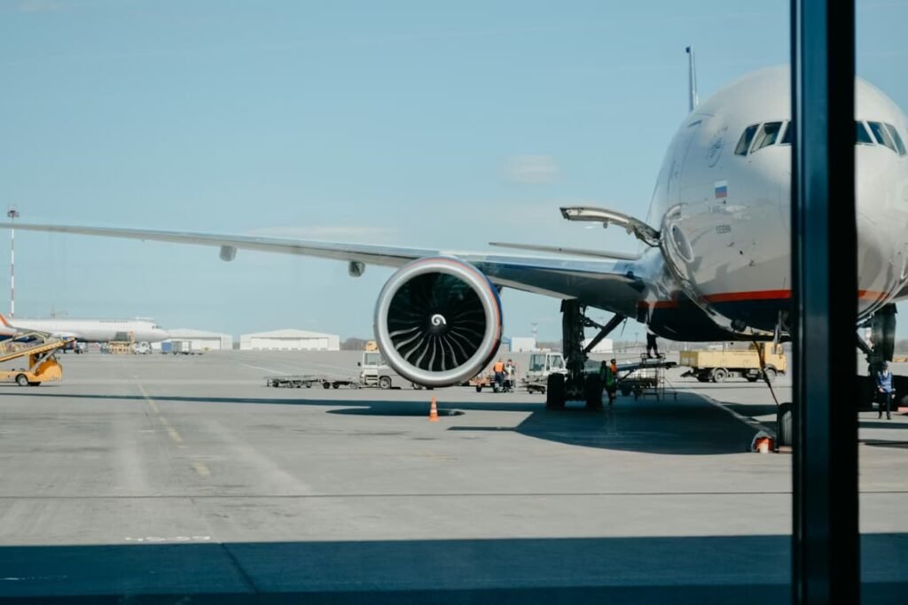 A close-up view of a large commercial airplane parked at an airport terminal gate on a sunny day. This visual helps travelers visualize their journey when they fly to Florida on a budget.