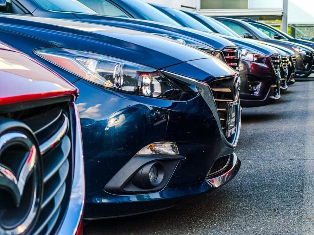 A row of modern Mazda cars parked at a rental car agency. This illustrates the rental car selection process for travelers who want to fly to Florida on a budget and choose the best value vehicle.