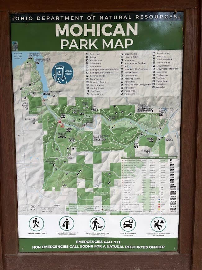 Planning a Mohican State Park hiking day trip? A detailed, official Ohio Department of Natural Resources trail map for Mohican State Park posted on a wooden outdoor kiosk display.