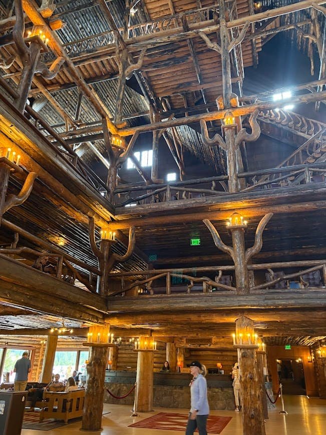 Old Faithful Inn lobby interior featuring massive log columns and multi-story rustic wooden balconies in Yellowstone National Park.